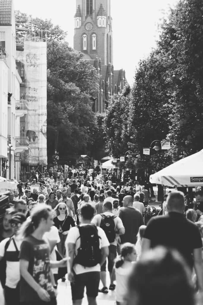 A black and white photo capturing a busy street filled with people in Sopot, Poland during the day.
