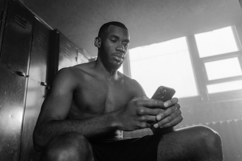A black and white photo of a man using smartphone indoors, conveying focus and calm.
